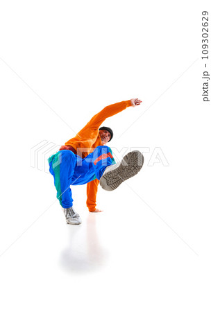 Young flexible sportive man dancing breakdance in vivid orange and blue sport uniform outfit against white studio background. 109302629