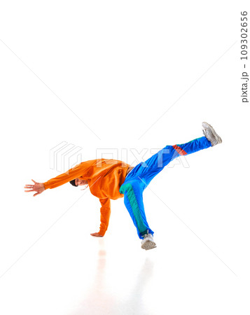 Stylishly dressed man, guy, professional dancer performing breakdance freezes, flexing in dace hall in motion against white background. 109302656