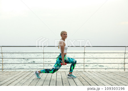 Young woman with dumbbells on wooden floor outdoors Young woman with dumbbells on wooden floor outdoors 109303196