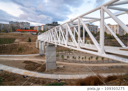 Iron pedestrian bridge over a small canyon painted in white. Tbilisi 109303275