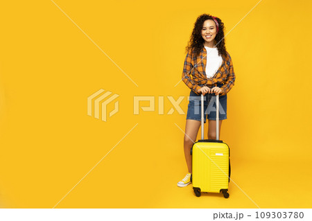 Young attractive girl with a yellow suitcase 109303780