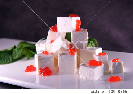 Feta cheese with red caviar decorated with herbs on a white plate. High quality photo Feta cheese with red caviar decorated with herbs on a white plate. High quality photo 109305669
