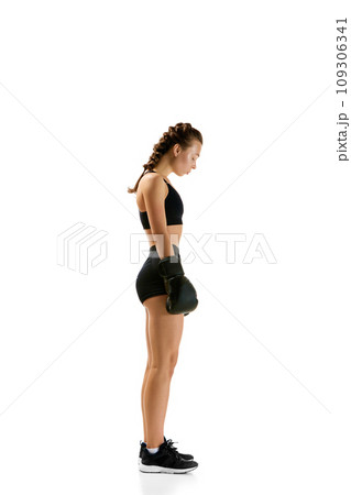 Side view portrait of determined young woman, professional boxer, confidently displaying her prowess in against white studio. Side view portrait of determined young woman, professional boxer, confidently displaying her prowess in against white studio. 109306341