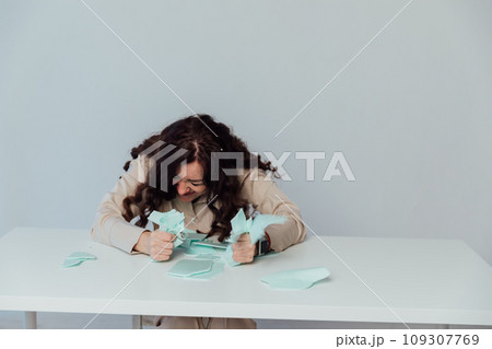 Beautiful brunette woman tearing paper at table negative emotions 109307769