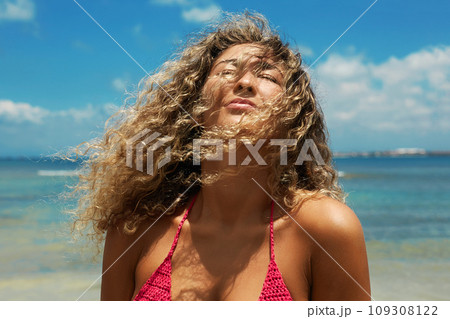 Beautiful happy woman on the beach. Smiling girl in Bikini near sea. Curty Hairstyle 109308122