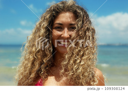 Beautiful happy woman on the beach. Smiling girl in Bikini near sea. Curty Hairstyle 109308124