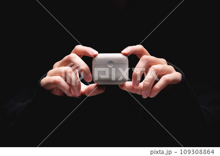 close-up of young woman hands holding wireless headphones charger. case for vacuum headphones on a black background close-up of young woman hands holding wireless headphones charger. case for vacuum headphones on a black background 109308864