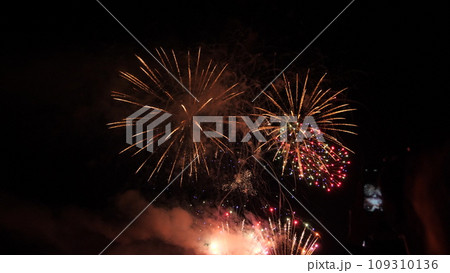 Fantastic fireworks show with sparkling blasts and smoke in black night sky. Fireworks dazzling display explode for party visitors at night. Abstract flash patterns at fireworks festival in dark sky Fantastic fireworks show with sparkling blasts and smoke in black night sky. Fireworks dazzling display explode for party visitors at night. Abstract flash patterns at fireworks festival in dark sky 109310136