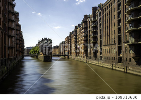 The Warehouse District (Speicherstadt) in Hamburg, Germany, on sunny day. View of Wandrahmsfleet. The largest warehouse district in the world is located in the port of Hamburg within the HafenCity The Warehouse District (Speicherstadt) in Hamburg, Germany, on sunny day. View of Wandrahmsfleet. The largest warehouse district in the world is located in the port of Hamburg within the HafenCity 109313630