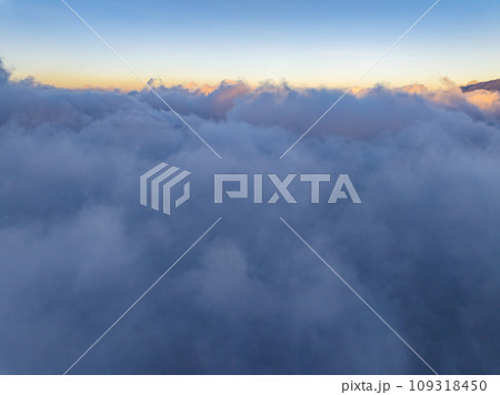Aerial view of flowing fog waves on mountain tropical rainforest,Bird eye view image over the clouds Amazing nature background with clouds and mountain peaks in indonesia 109318450