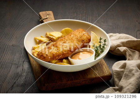 bowl of breaded fish fillet and fried potato wedges bowl of breaded fish fillet and fried potato wedges 109321296