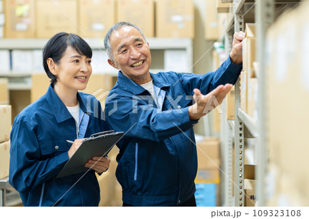 倉庫で打ち合わせをするミドルの男女の作業員 倉庫で打ち合わせをするミドルの男女の作業員 109323108
