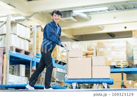 倉庫でハンドリフトを使って荷物を運ぶミドルの女性作業員 109323129
