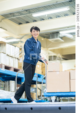 倉庫でハンドリフトを使って荷物を運ぶミドルの女性作業員 109323136