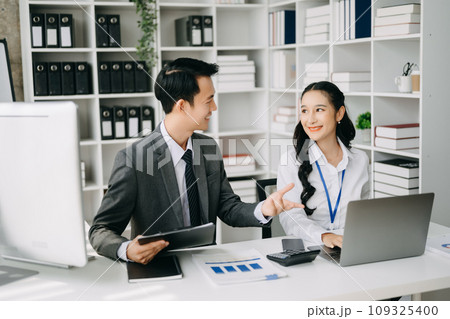 Two business workers talking on the smartphone and using laptop at the office. 109325400