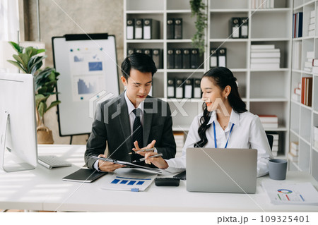 Two business workers talking on the smartphone and using laptop at the office. Two business workers talking on the smartphone and using laptop at the office. 109325401