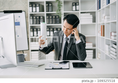 Asian business man is stressed, bored, and overthinking from working on a tablet at the office. 109325518