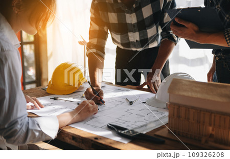 Two colleagues discussing data working and tablet, laptop with on on architectural project at construction site at desk in office 109326208