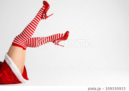 Sexy Santa woman legs in red shoes and striped socks 109330915