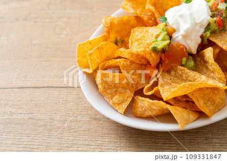nachos tortilla chips with jalapeno, guacamole, tomatoes salsa and dip nachos tortilla chips with jalapeno, guacamole, tomatoes salsa and dip 109331847