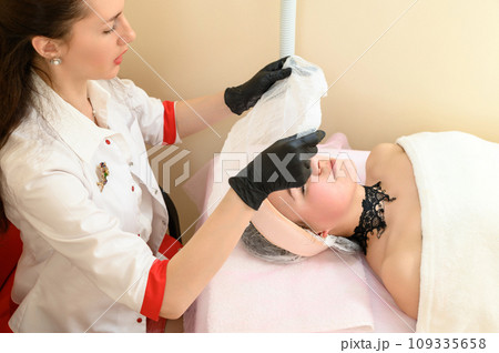A beautician puts gauze on the patient's face A beautician puts gauze on the patient's face 109335658