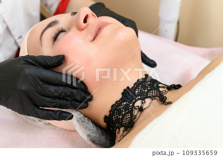 A beautician gives a relaxing face massage to a girl. A beautician gives a relaxing face massage to a girl. 109335659
