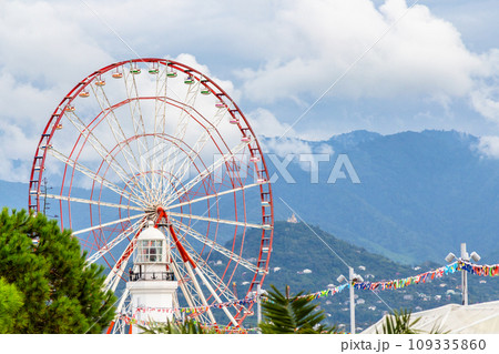 view of Ferris wheel, old lighthouse and mountains 109335860