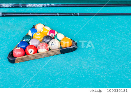 old billiard balls in wooden rack on green table old billiard balls in wooden rack on green table 109336181
