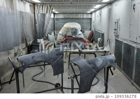 The photograph captures the scene of an automotive workshop, showcasing the process of painting various car parts. Different components of the vehicle car bonnet, bumpers, smaller details. The photograph captures the scene of an automotive workshop, showcasing the process of painting various car parts. Different components of the vehicle car bonnet, bumpers, smaller details. 109336278