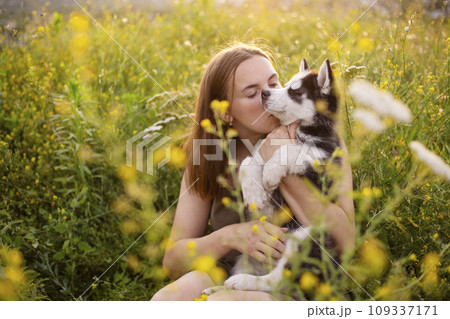 Beautiful young caucasian woman is playing with her puppy dog outdoor. 109337171