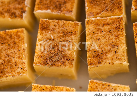 Homemade eggnog fudge pieces on a white cutting board. 109338035