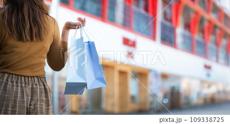 Happy beautiful young stylish woman with shopping bag while walking come out of mall on holiday Happy beautiful young stylish woman with shopping bag while walking come out of mall on holiday 109338725