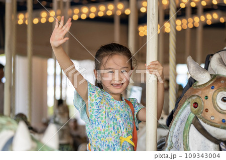 メリーゴーランドに乗ってはしゃぐ女の子 109343004