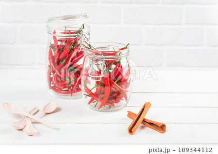 Spices seasoning chili pepper in glass bottle and cinnamon on table Spices seasoning chili pepper in glass bottle and cinnamon on table 109344112