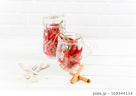 Spices seasoning chili pepper in glass bottle and cinnamon on table Spices seasoning chili pepper in glass bottle and cinnamon on table 109344114