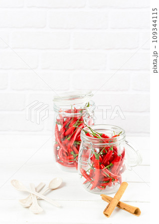 Spices seasoning chili pepper in glass bottle and cinnamon on table 109344115