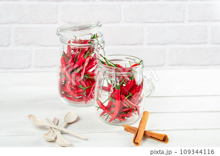 Spices seasoning chili pepper in glass bottle and cinnamon on table 109344116