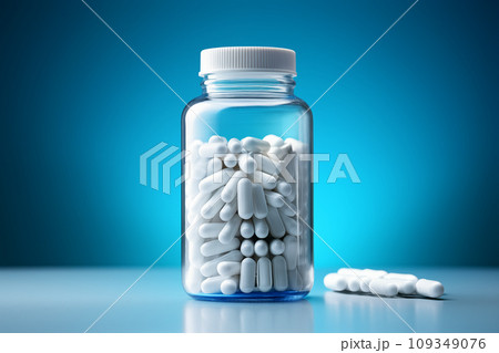 Transparent bottle filled with white capsules against a blue harmony backdrop 109349076