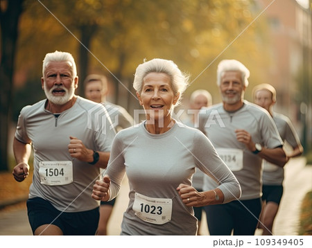 Senior grey haired men and women running a marathon race in a multi generation group of people in the park Senior grey haired men and women running a marathon race in a multi generation group of people in the park 109349405