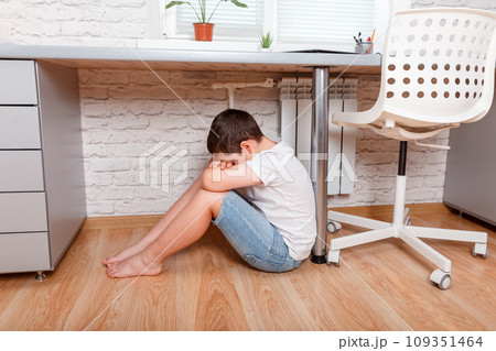 Boy upset. Teenage boy sit alone under desk, covering his face Boy upset. Teenage boy sit alone under desk, covering his face 109351464