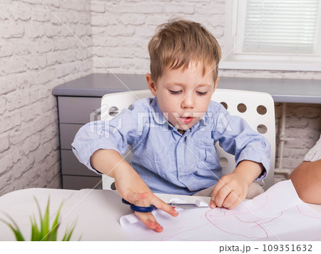 Craft for children. Kid cutting with scissors and gluing paper. 109351632