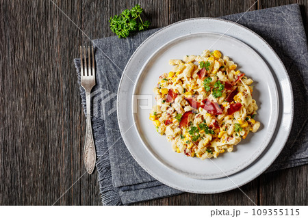 macaroni and cheese with corn, bacon topped with panko breadcrumbs on plate on dark wooden table with fork 109355115