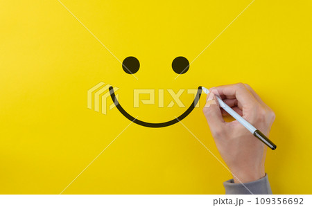 Customer review satisfaction feedback survey concept. Hand using pen to draw happy smiling face on yellow background. Service product evaluation business, Positive thinking, Mental health assessment, Customer review satisfaction feedback survey concept. Hand using pen to draw happy smiling face on yellow background. Service product evaluation business, Positive thinking, Mental health assessment, 109356692