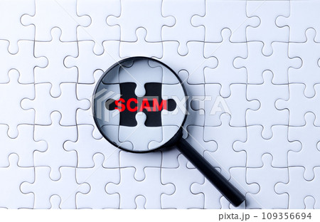 The concept of technology to counter fraud and scam. Hand holding a magnifying glass focusing on scam word on a jigsaw puzzle. Internet fraud, Online scam, Phishing alert, 109356694