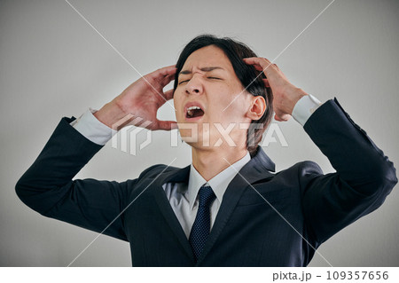 頭を抱えてショックを受ける若い男性会社員 109357656