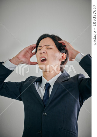 頭を抱えてショックを受ける若い男性会社員 頭を抱えてショックを受ける若い男性会社員 109357657