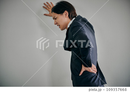 腰が痛くて手で押さえる若い男性会社員 腰が痛くて手で押さえる若い男性会社員 109357668