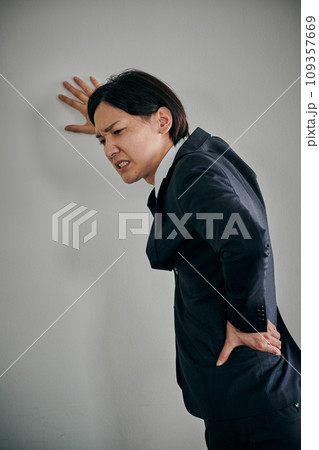 腰が痛くて手で押さえる若い男性会社員 腰が痛くて手で押さえる若い男性会社員 109357669