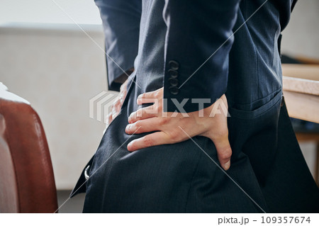 腰が痛くて手で押さえる若い男性会社員 腰が痛くて手で押さえる若い男性会社員 109357674