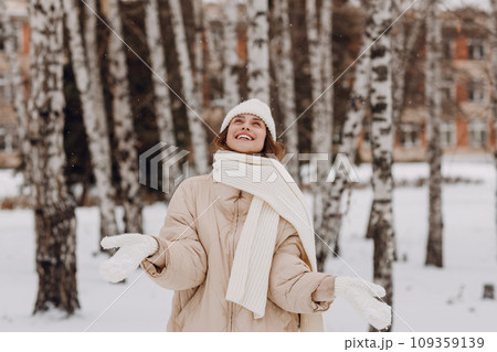 Happy smiling young woman portrait dressed coat scarf hat and mittens enjoys winter weather at birch winter park 109359139